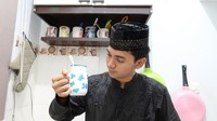 Dengan mengenakan pakaian Muslim lengkap kopiah, Ajil Ditto memamerkan dirinya yang baru saja membuat minuman menggunakan gelas lucu. Kira-kira minuman apa ya yang dibuat oleh Ajil? Foto: Instagram @ajil_ditto08