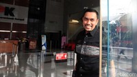 Sahroni tampak melempar senyuman kepada wartawan yang menunggunya.