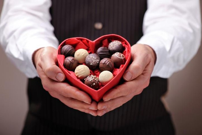 Red roses and chocolate candy on a wooden table