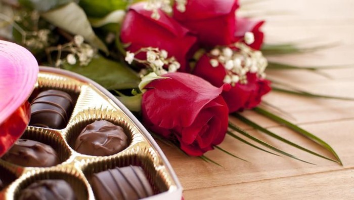 cokelat valentine Red roses and chocolate candy on a wooden table