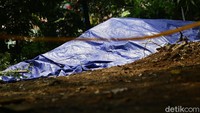 Gundukan tanah yang ditutupi terpal itu berjarak sekitar lima meter dari rumah warga.