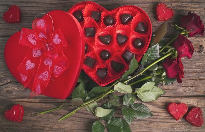 Red roses and chocolate candy on a wooden table
