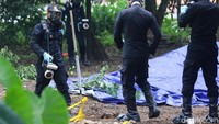 Saat mendekati gundukan tanah yang ditutupi plastik terpal, personel menggunakan masker wajah, sarung tangan, dan pelindung alas kaki.