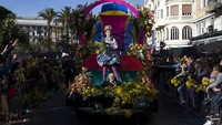 Seorang peserta parade Karnaval Nice ke-136 menebarkan bunga kepada para pengunjung yang antusias menyaksikan parade tersebut.