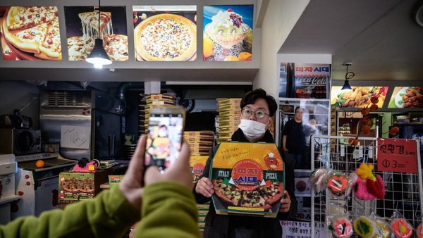 Turis datang tak cuma untuk makan, tapi sekaligus untuk foto di Sky Pizza yang digunakan syuting film Parasite. (ED JONES/AFP)