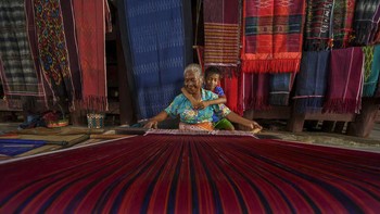Potret seorang ibu yang sedang membuat ulos dan ditemani oleh putranya ini diabadaikan oleh georock888 di Pulau Samosir, Sumatera Utara, Indonesia. Istimewa/Dok. Boredpanda/Agora Images.