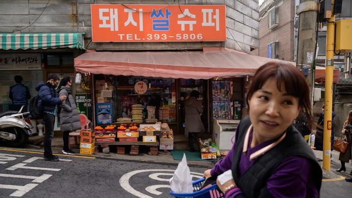 SKOREA-ENTERTAINMENT-FILM-PARASITE-OSCARS-TOURISM Pizza restaurant owner Eom Hang-ki, 65, sits before a photo of her with film director Bong Joon-ho in her restaurant 'Sky Pizza' in Seoul on February 13, 2020. - Locations featured in the South Korea's Oscar-winning