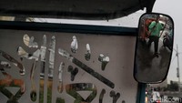 Di tengah guyuran hujan, seorang bapak tetap menarik gerobak.