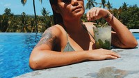 Wanita bertato ini tak melewatkan berenang saat di Pulau Dewata. Untuk menyegarkan tenggorokannya, ia memilih segelas mocktail segar. Foto: Instagram wulanrussell
