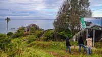 Wisatawan melihat papan informasi lokasi wisata Batu Sindu di kawasan Tanjung Senubing.