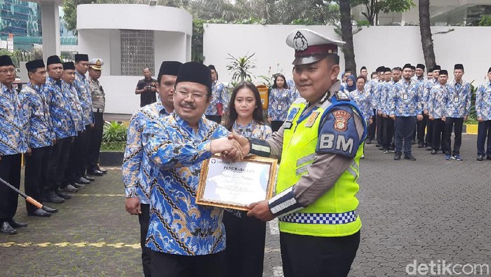Ketua Ombudsman Amzulian Rifai memberikan penghargaan kepada Bripka Sigit Prabowo yang menggendong warga terkena serangan jantung.