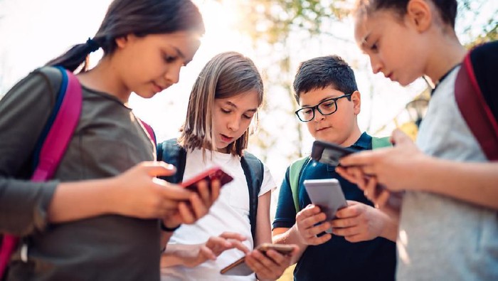 Group of kids playing video games on smart phone after school