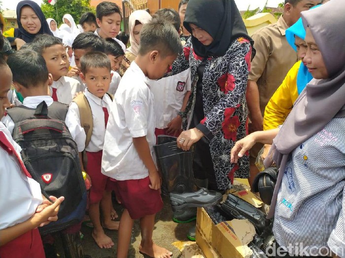 Siswa SD Nengeri Banjarasri, Kecamatan Tanggualangin Sidoarjo terdampak banjir dalam satu bulan terakhir. Kini mereka senang bisa belajar menggunakan sepatu bot.