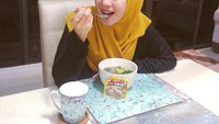 Jika tadi menyantap sashimi salmon, kini Bella dengan memakai jilbab kuning cerah sedang menyantap sup ayam yang hangat. Ia menyantap ini sambil mempromosikan sebuah merek untuk penyedap rasa. Foto: Instagram @laudyacynthiabella