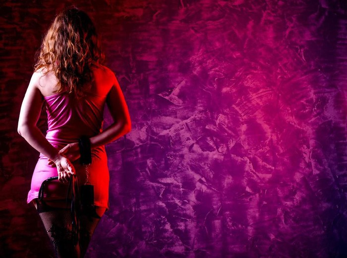 Girl in bdsm with handcuffs and whip, free space for your text. Role-playing games.