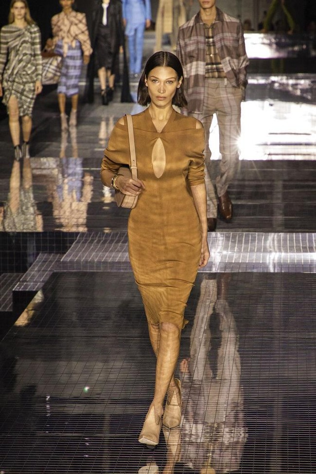 Bella Hadid muncul dalam balutan dress coklat dengan aksen key-hole yang seksi di area dada. Busana rancangan Riccardo Tisci itu dimaksimalkan dengan handbag kulit dan heels senada. (Foto: Vianney Le Caer/Invision/AP)