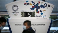 Seorang warga tampak mengenakan masker pelindung pernapasan saat lalu lalang di depan papan hitung mundur pelaksanaan Olimpiade Tokyo 2020 di kawasan Tokyo, Jepang, Selasa (18/2/2020). AP Photo/Jae C. Hong.
