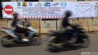 Sejumlah kendaraan melintas di depan spanduk pemberitahuan penutupan jalan di Cikunir, Bekasi, Jawa Barat, Selasa (18/2/2020).