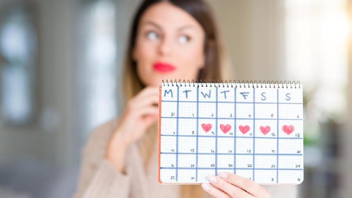 Menghitung masa subur Young beautiful woman holding menstruation calendar at home serious face thinking about question, very confused idea