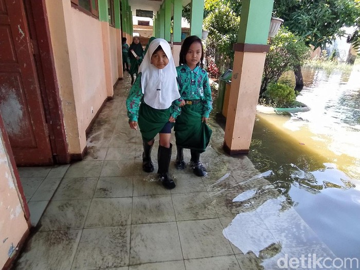 Siswa-siswi SD Negeri Banjarasri, Kecamatan Tanggulangin, Sidiarjo mulai memakai sepatu seragam saat masuk kelas. Yakni sepatu bot karena halaman dan kelas terendam banjir.