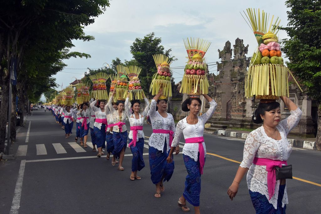 Sejumlah perempuan Bali mengusung Gebogan atau sesajen berisi buah, kue, bunga dan hiasan janur dalam tradisi Mapeed yaitu rangkaian persembahyangan Hari Raya Galungan di Desa Lukluk, Badung, Bali, Rabu (19/2/2020). Tradisi parade sesajen tersebut dilakukan menjelang persembahyangan bersama di Pura Dalem dalam merayakan hari kemenangan 