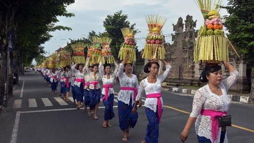 Sejumlah perempuan Bali mengusung Gebogan atau sesajen berisi buah, kue, bunga dan hiasan janur dalam tradisi Mapeed yaitu rangkaian persembahyangan Hari Raya Galungan di Desa Lukluk, Badung, Bali, Rabu (19/2/2020). Tradisi parade sesajen tersebut dilakukan menjelang persembahyangan bersama di Pura Dalem dalam merayakan hari kemenangan 