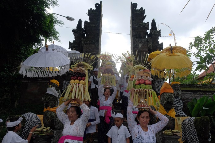 Sejumlah perempuan Bali mengusung Gebogan atau sesajen berisi buah, kue, bunga dan hiasan janur dalam tradisi Mapeed yaitu rangkaian persembahyangan Hari Raya Galungan di Desa Lukluk, Badung, Bali, Rabu (19/2/2020). Tradisi parade sesajen tersebut dilakukan menjelang persembahyangan bersama di Pura Dalem dalam merayakan hari kemenangan 
