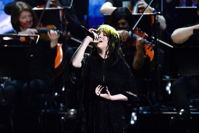 Gaya Billie Eilish lalu berubah total saat beraksi di panggung Brit Awards 2020 bersama Finneas dan komposer film Hans Zimmer. Melantunkan lagu No Time To Die yang merupakan soundtrack film James Bond terbaru, Billie memakai busana serba hitam. Selain sebagai performer, Billie juga berhasil menyabet penghargaan Brit untuk kategori International Female Solo Artist. (Foto: Gareth Cattermole/Getty Images)