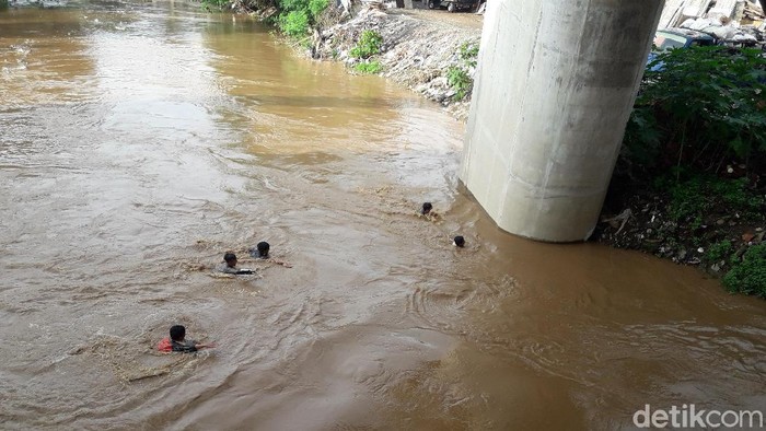 Anak-anak Rawajati berenang di Ciliwung yang meluap saat banjir. (Muhammad Ilman Nafian/detikcom)