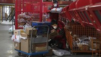Para petugas dengan mengenakan masker pelindung pernapasan dan sarung tangan menyortir berbagai paket pesanan sebelum dikirimkan ke pemesan.