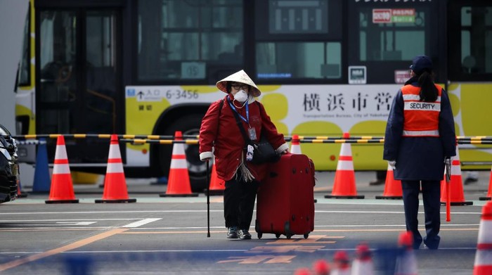 An unidentified passenger walks down after she disembarked from the quarantined Diamond Princess cruise ship Wednesday, Feb. 19, 2020, in Yokohama, near Tokyo. Passengers tested negative for COVID-19 started disembarking Wednesday. (AP Photo/Jae C. Hong)