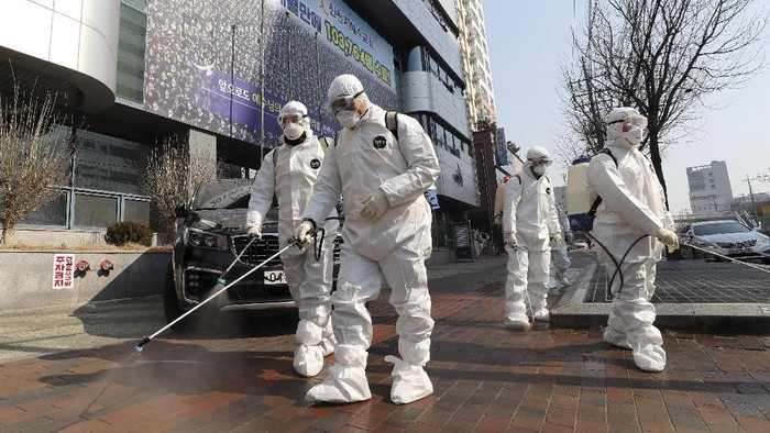 Workers wearing protective gears spray disinfectant against the new coronavirus in front of a church in Daegu, South Korea, Thursday, Feb. 20, 2020. The mayor of the South Korean city of Daegu urged its 2.5 million people on Thursday to refrain from going outside as cases of the new virus spike. (Kim Jun-beom/Yonhap via AP)