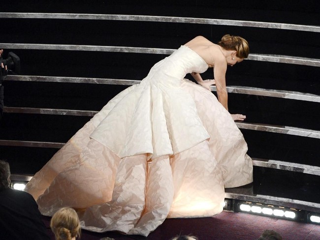 Salah satu kejadian yang tak terlupakan bagi Jennifer Lawrence adalah ketika ia terjatuh di tangga ketika akan mengambil piala Oscar-nya di 2013. Kala itu, Jen tak sengaja menginjak gaunnya hingga terjatuh. Foto: Getty Images