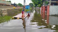 Tak hanya bersih-bersih, tampak pula dua orang anak bermain air di tengah banjir yang mulai surut.