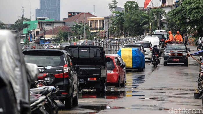 Warga memarkir kendaraan roda 4 di jalan Inspeksi Kali Ciliwung, Jakarta, Jumat (21/2/2020). Jalan tersebut merupakan hasil normalisasi pelebaran sungai Ciliwung di kawasan Kampung Pulo (sisi timur) dan Bukit Duri (sisi barat) beberapa waktu lalu. Namun, arus lalu-lintas yang tidak ramai membuat warga menjadikan satu lajur jalan sebagai lahan parkir tetap layaknya garasi mobil di rumah. Beberapa menggunakan penutup badan mobil untuk menghindari sinar matahari dan hujan. Rumah di sisi jalan hanya gang yang tidak terdapat akses untuk mobil.