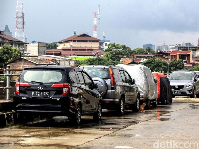 Warga memarkir kendaraan roda 4 di jalan Inspeksi Kali Ciliwung, Jakarta, Jumat (21/2/2020). Jalan tersebut merupakan hasil normalisasi pelebaran sungai Ciliwung di kawasan Kampung Pulo (sisi timur) dan Bukit Duri (sisi barat) beberapa waktu lalu. Namun, arus lalu-lintas yang tidak ramai membuat warga menjadikan satu lajur jalan sebagai lahan parkir tetap layaknya garasi mobil di rumah. Beberapa menggunakan penutup badan mobil untuk menghindari sinar matahari dan hujan. Rumah di sisi jalan hanya gang yang tidak terdapat akses untuk mobil.