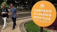 Sejumlah warga melintas di samping papan penanda bertulliskan Kawasan Dilarang Merokok yang berada di area Taman Balai Kota Bandung, Jawa Barat, Jumat (21/2/2020).