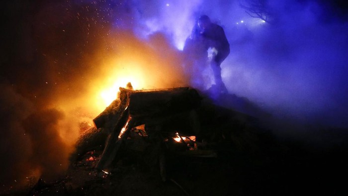 A protester, who planned to stop buses carrying passengers evacuated from the Chinese city of Wuhan, kindles a fire outside Novi Sarzhany, Ukraine, Thursday, Feb. 20, 2020. Several hundred residents in Ukraines Poltava region protested to stop officials from quarantining the evacuees in their village because they feared becoming infected. Demonstrators put up road blocks and burned tires, while Ukrainian media reported that there were clashes with police, and more than 10 people were detained. (AP Photo/Efrem Lukatsky)