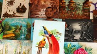 Seorang pedagang menunjukkan lukisan yang dijualnya di Jalan Braga, Bandung.