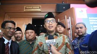 Peci hitam dengan logo NU tersebut dipadu dengan batik.