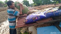 Seorang warga tengah menjemur sejumlah bantal yang basah akibat terendam banjir.