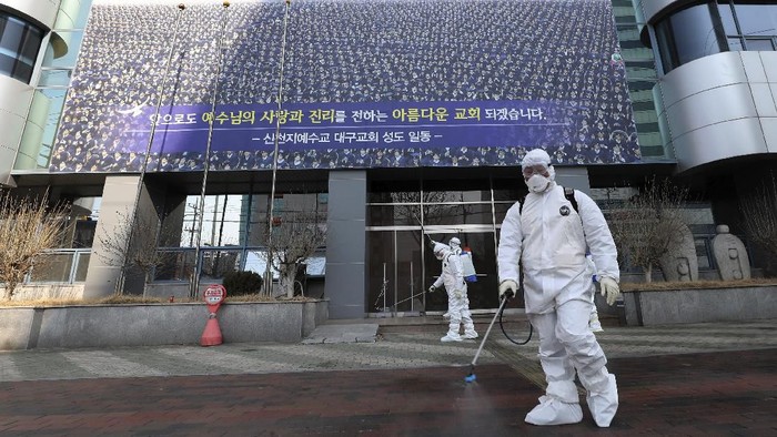 In this Thursday, Feb. 20, 2020, photo, workers wearing protective gears spray disinfectant against the new coronavirus in front of the Shincheonji church in Daegu, South Korea. South Korea on Friday, Feb. 21, declared a 