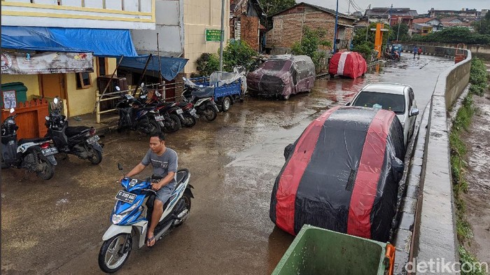 Warga memarkir kendaraan roda 4 di jalan Inspeksi Kali Ciliwung, Jakarta, Jumat (21/2/2020). Jalan tersebut merupakan hasil normalisasi pelebaran sungai Ciliwung di kawasan Kampung Pulo (sisi timur) dan Bukit Duri (sisi barat) beberapa waktu lalu. Namun, arus lalu-lintas yang tidak ramai membuat warga menjadikan satu lajur jalan sebagai lahan parkir tetap layaknya garasi mobil di rumah. Beberapa menggunakan penutup badan mobil untuk menghindari sinar matahari dan hujan. Rumah di sisi jalan hanya gang yang tidak terdapat akses untuk mobil.