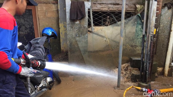 Petugas dan warga membersihkan lumpur sisa banjir di Rawajati, Pancoran, Jakarta Selatan