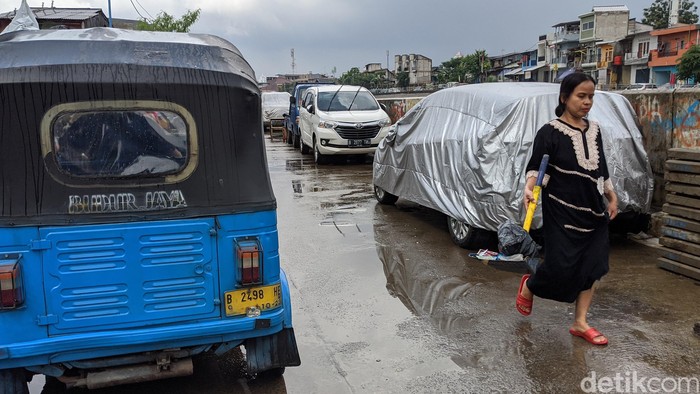 Warga memarkir kendaraan roda 4 di jalan Inspeksi Kali Ciliwung, Jakarta, Jumat (21/2/2020). Jalan tersebut merupakan hasil normalisasi pelebaran sungai Ciliwung di kawasan Kampung Pulo (sisi timur) dan Bukit Duri (sisi barat) beberapa waktu lalu. Namun, arus lalu-lintas yang tidak ramai membuat warga menjadikan satu lajur jalan sebagai lahan parkir tetap layaknya garasi mobil di rumah. Beberapa menggunakan penutup badan mobil untuk menghindari sinar matahari dan hujan. Rumah di sisi jalan hanya gang yang tidak terdapat akses untuk mobil.