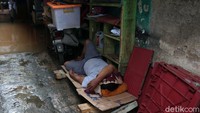 Seorang warga tidur di saat rumahnya kebanjiran di kawasan Cipinang Melayu, Jakarta, Minggu (23/2).