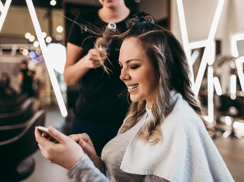 1138252831 Beautiful brunette woman with long hair at the beauty salon getting a hair blowing. Hair salon styling concept.
