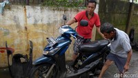 Seorang warga mencoba melakukan starter engkol untuk menghidupkan motor yang tengah diperbaiki.