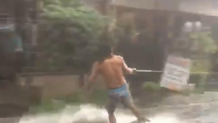 Pria berselancar di jalan yang tergenang banjir