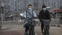 Seorang pria dan wanita tampak mengendarai sepeda di kawasan Beijing, China. Keduanya juga tampak mengenakan masker pelindung pernapasan saat beraktivitas di luar ruangan guna mencegah terinfeksi virus corona. Getty Images/Kevin Frayer.